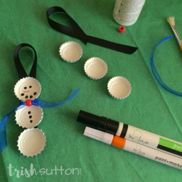 Upcycle bottle caps to create cute Christmas tree ornaments. This simple creation is perfect for kids & adults alike. Bottle Cap Snowman Ornament. TrishSutton.com